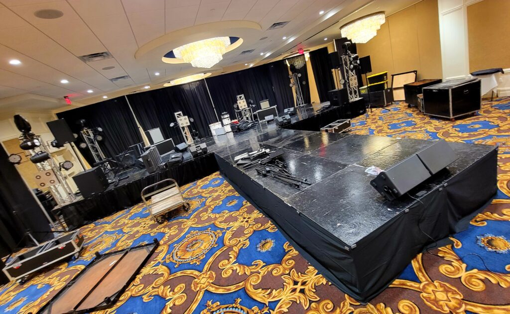 Black Stage set up on blue and gold patterned carpet in banquet hall